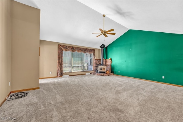 unfurnished living room with lofted ceiling, a ceiling fan, carpet, baseboards, and a wood stove