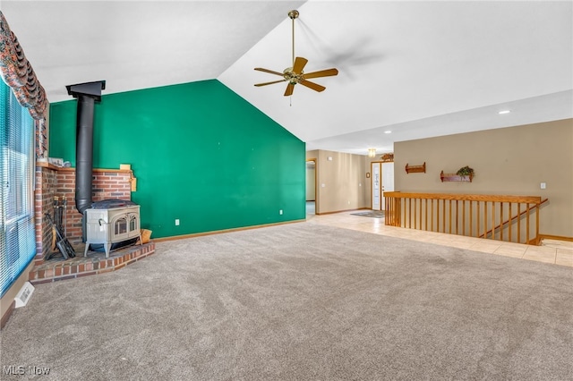 unfurnished living room with visible vents, ceiling fan, lofted ceiling, carpet flooring, and a wood stove