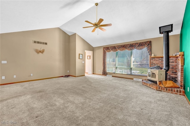 unfurnished living room with visible vents, baseboards, carpet, ceiling fan, and a wood stove