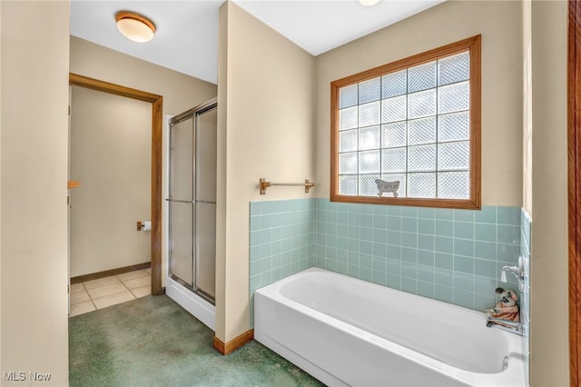 bathroom with a shower stall, a bath, baseboards, and tile patterned floors