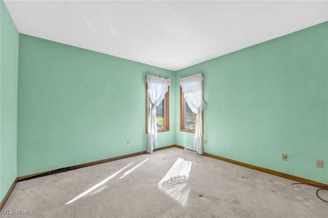 spare room featuring carpet flooring and baseboards