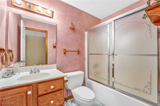 bathroom featuring bath / shower combo with glass door, vanity, and toilet