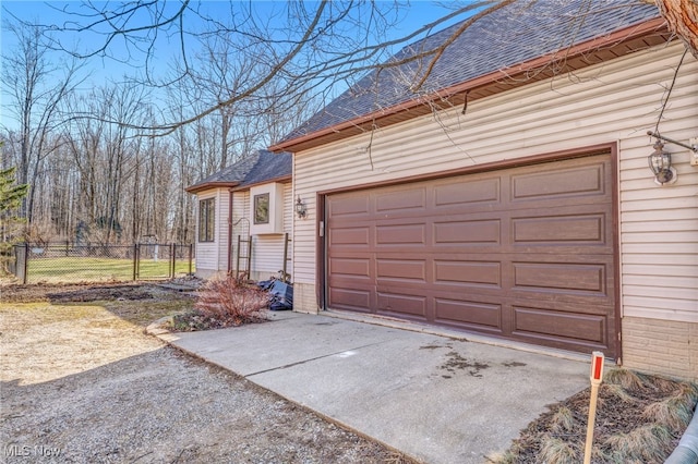 garage with concrete driveway and fence