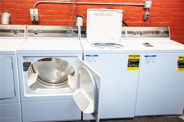 laundry room with independent washer and dryer and brick wall