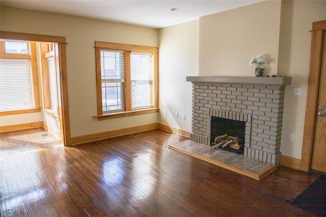 unfurnished living room featuring hardwood / wood-style floors, visible vents, a fireplace, and baseboards