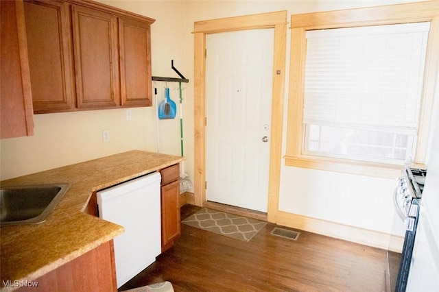 kitchen featuring visible vents, brown cabinets, dark wood-style floors, stainless steel range with gas cooktop, and dishwasher