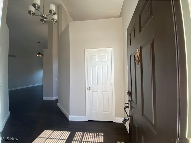 corridor with baseboards, dark wood-type flooring, and a chandelier