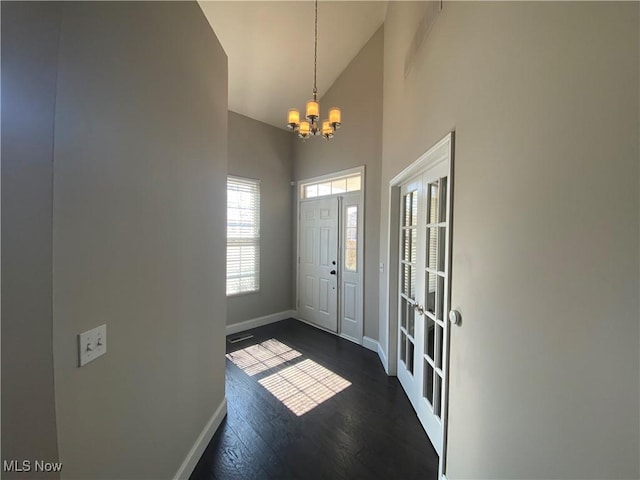 foyer entrance featuring visible vents, baseboards, high vaulted ceiling, an inviting chandelier, and dark wood-type flooring