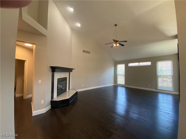 unfurnished living room featuring a tiled fireplace, visible vents, ceiling fan, and wood finished floors