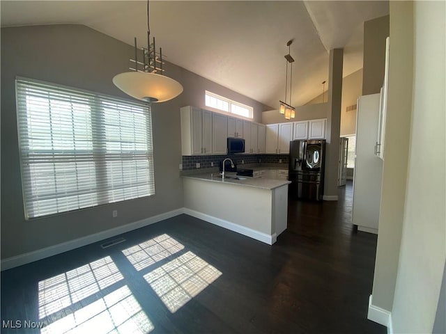 kitchen featuring visible vents, a peninsula, a sink, black appliances, and light countertops