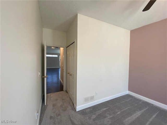 carpeted empty room with visible vents, baseboards, and ceiling fan