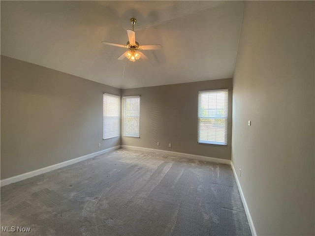 carpeted empty room featuring baseboards, ceiling fan, and vaulted ceiling