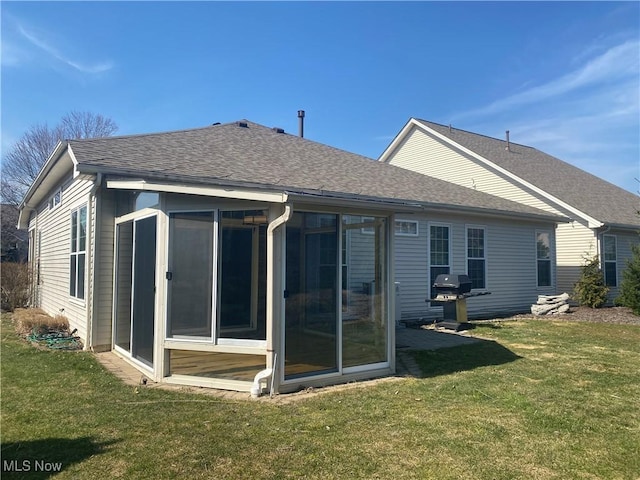 back of property featuring a sunroom, a yard, and roof with shingles