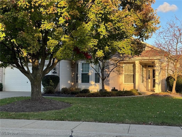 view of property hidden behind natural elements featuring a garage, driveway, and a front lawn