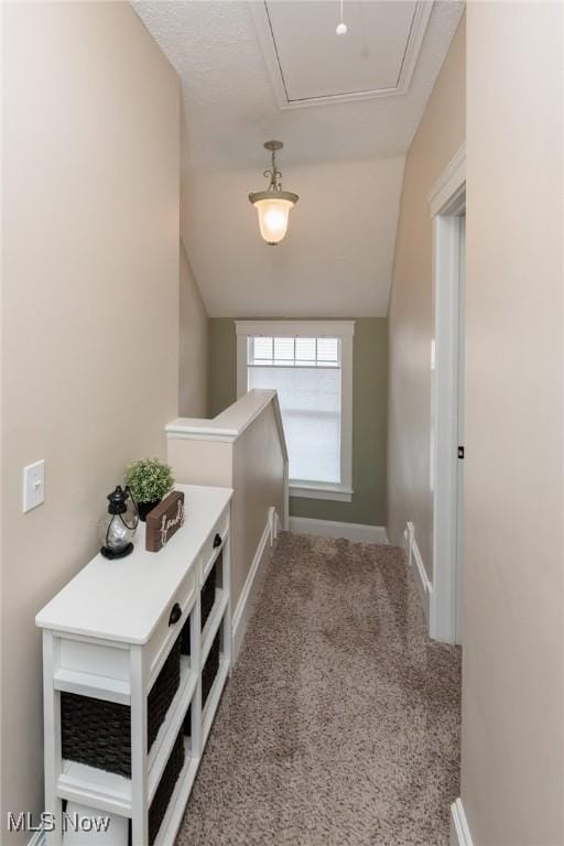 hall featuring baseboards, attic access, lofted ceiling, carpet flooring, and an upstairs landing