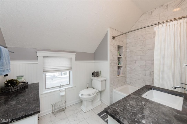 bathroom featuring lofted ceiling, toilet, and wainscoting