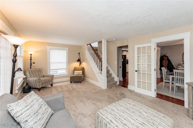 living area featuring stairway, carpet, baseboards, french doors, and a textured ceiling