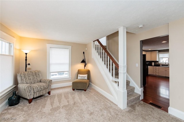 living area featuring stairs, plenty of natural light, and baseboards