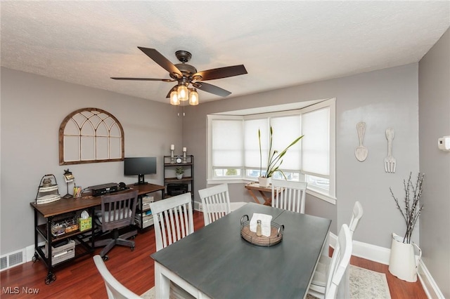 dining area featuring a ceiling fan, visible vents, wood finished floors, baseboards, and a textured ceiling