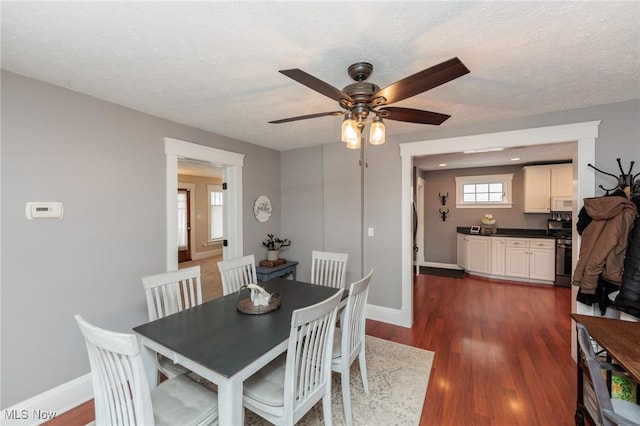 dining room with baseboards, a textured ceiling, dark wood-style floors, and a ceiling fan