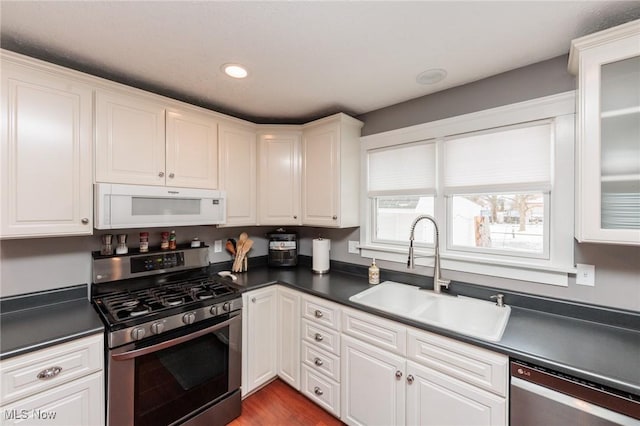 kitchen featuring a sink, dark countertops, white cabinets, and stainless steel appliances