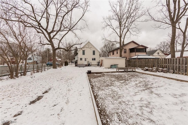 yard layered in snow featuring an outbuilding and a fenced backyard