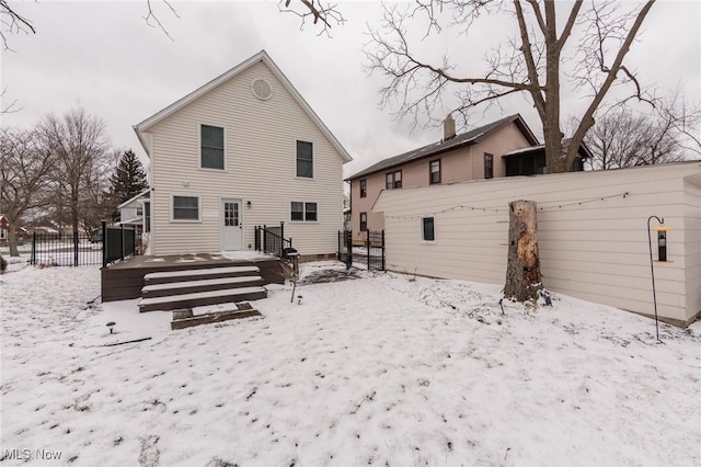 snow covered house featuring fence