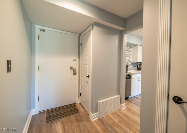 corridor featuring a sink, baseboards, visible vents, and light wood-type flooring