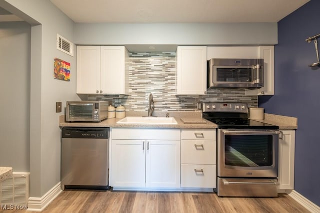 kitchen with visible vents, backsplash, appliances with stainless steel finishes, and a sink