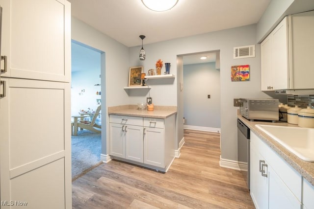 kitchen featuring light wood finished floors, visible vents, light countertops, and a sink