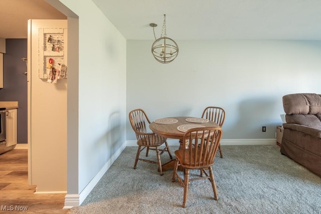 dining space featuring light carpet, a chandelier, light wood finished floors, and baseboards