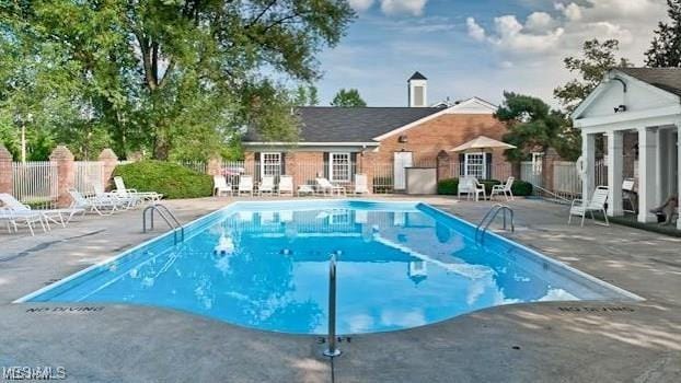 community pool featuring fence and a patio area