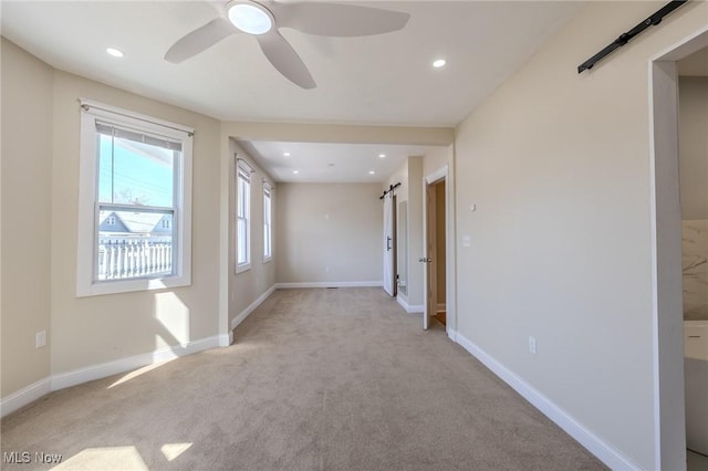 empty room with light carpet, baseboards, and a barn door