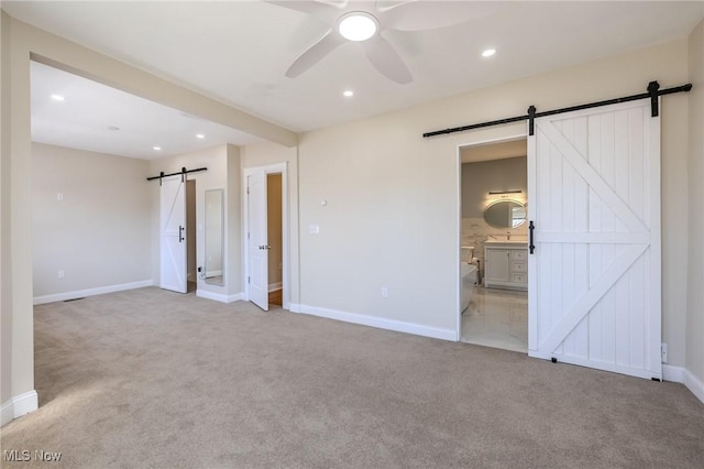 unfurnished bedroom featuring recessed lighting, a barn door, baseboards, and light colored carpet