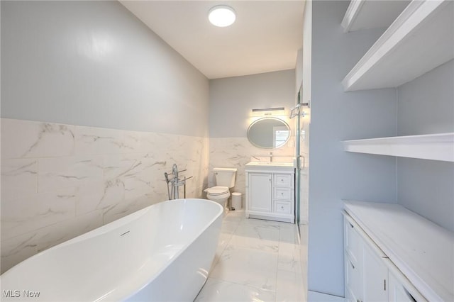 bathroom with vanity, a freestanding tub, tile walls, toilet, and marble finish floor