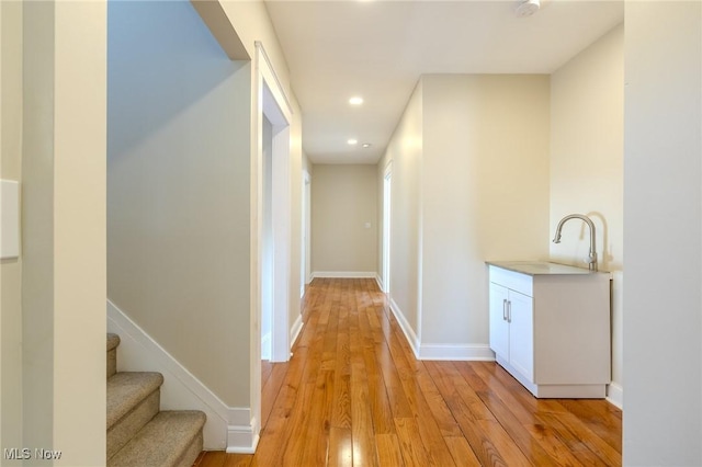 hall with recessed lighting, baseboards, light wood finished floors, and a sink