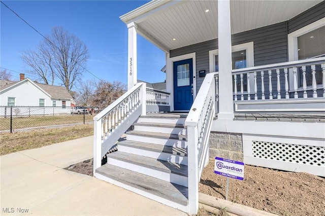 doorway to property with a porch and fence