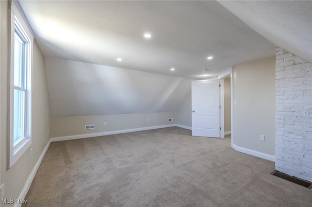 interior space with baseboards, visible vents, carpet floors, recessed lighting, and vaulted ceiling