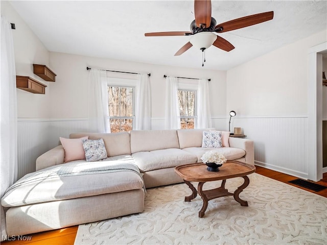 living room featuring visible vents, wainscoting, a ceiling fan, and wood finished floors