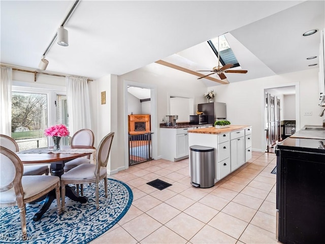 kitchen with light tile patterned floors, white cabinets, butcher block counters, and a sink