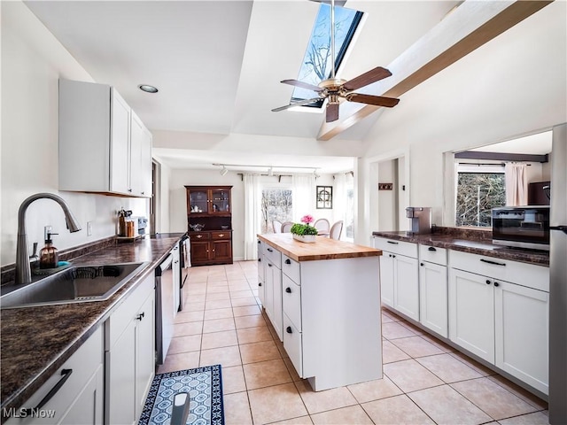 kitchen with wooden counters, light tile patterned floors, appliances with stainless steel finishes, white cabinetry, and a sink