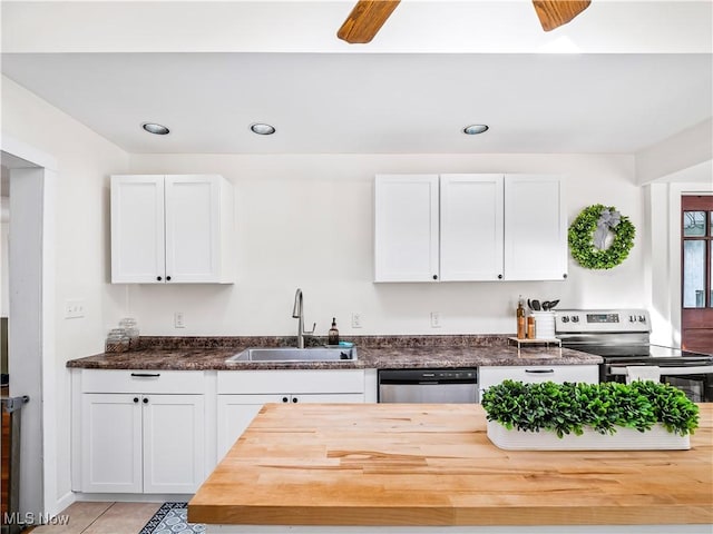 kitchen featuring butcher block countertops, a sink, appliances with stainless steel finishes, white cabinets, and light tile patterned floors