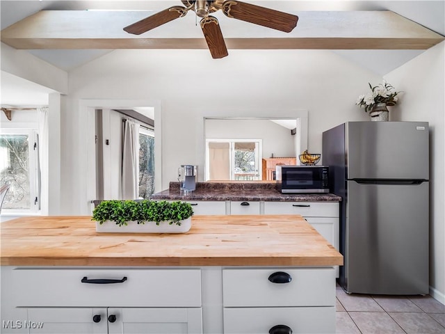 kitchen featuring butcher block countertops, vaulted ceiling, plenty of natural light, white cabinets, and stainless steel appliances