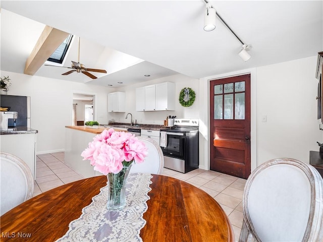 dining room with track lighting, a ceiling fan, light tile patterned floors, a healthy amount of sunlight, and vaulted ceiling