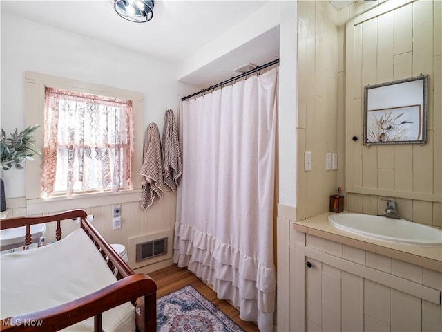 bathroom with vanity, a shower with curtain, wood finished floors, visible vents, and wood walls