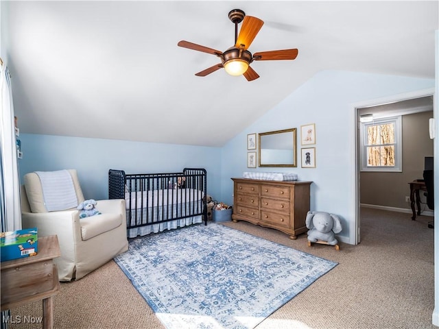 carpeted bedroom featuring a crib, lofted ceiling, baseboards, and ceiling fan