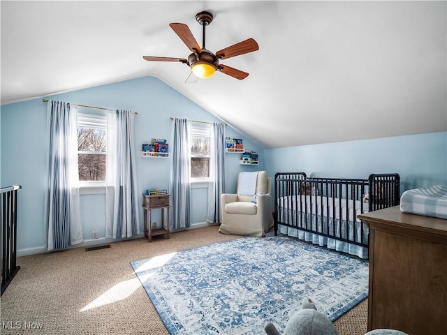 carpeted bedroom with visible vents, lofted ceiling, a crib, and a ceiling fan