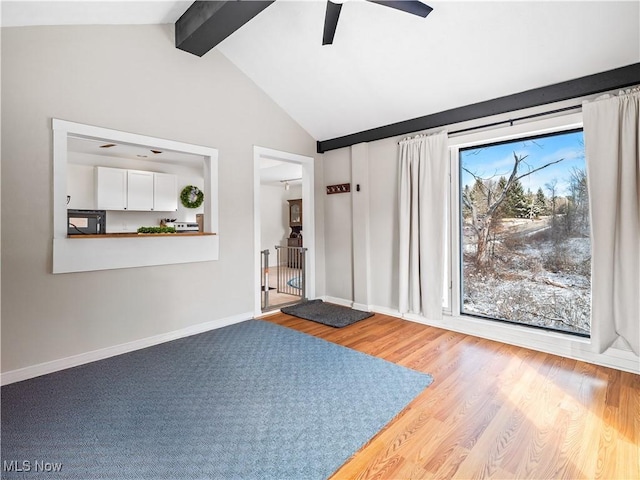 interior space featuring baseboards, lofted ceiling with beams, ceiling fan, and wood finished floors