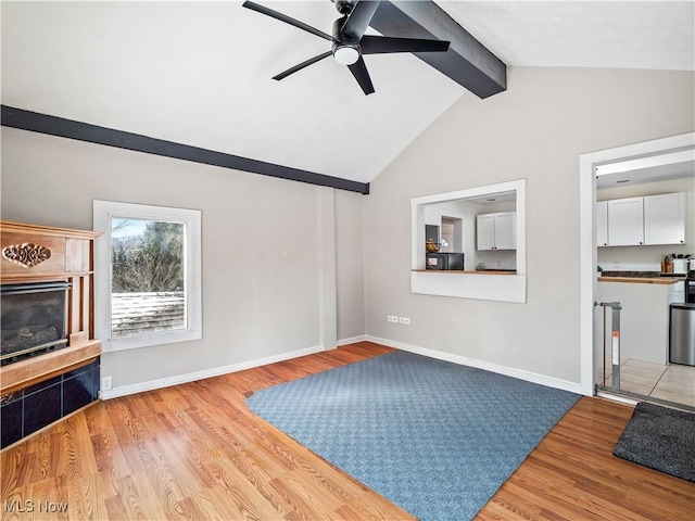 unfurnished living room with ceiling fan, baseboards, wood finished floors, and vaulted ceiling with beams