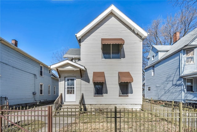 rear view of property featuring entry steps and a fenced front yard